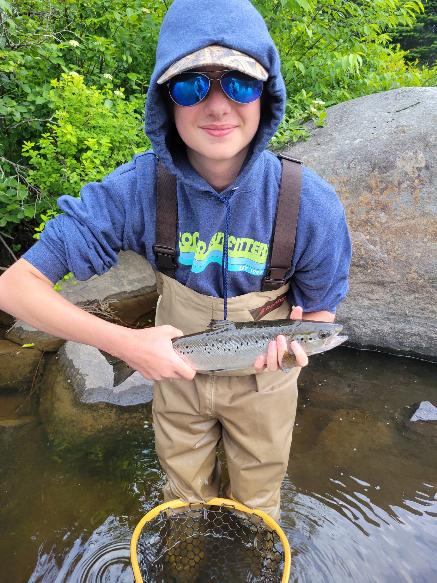 Child in fishing waders holding a fish