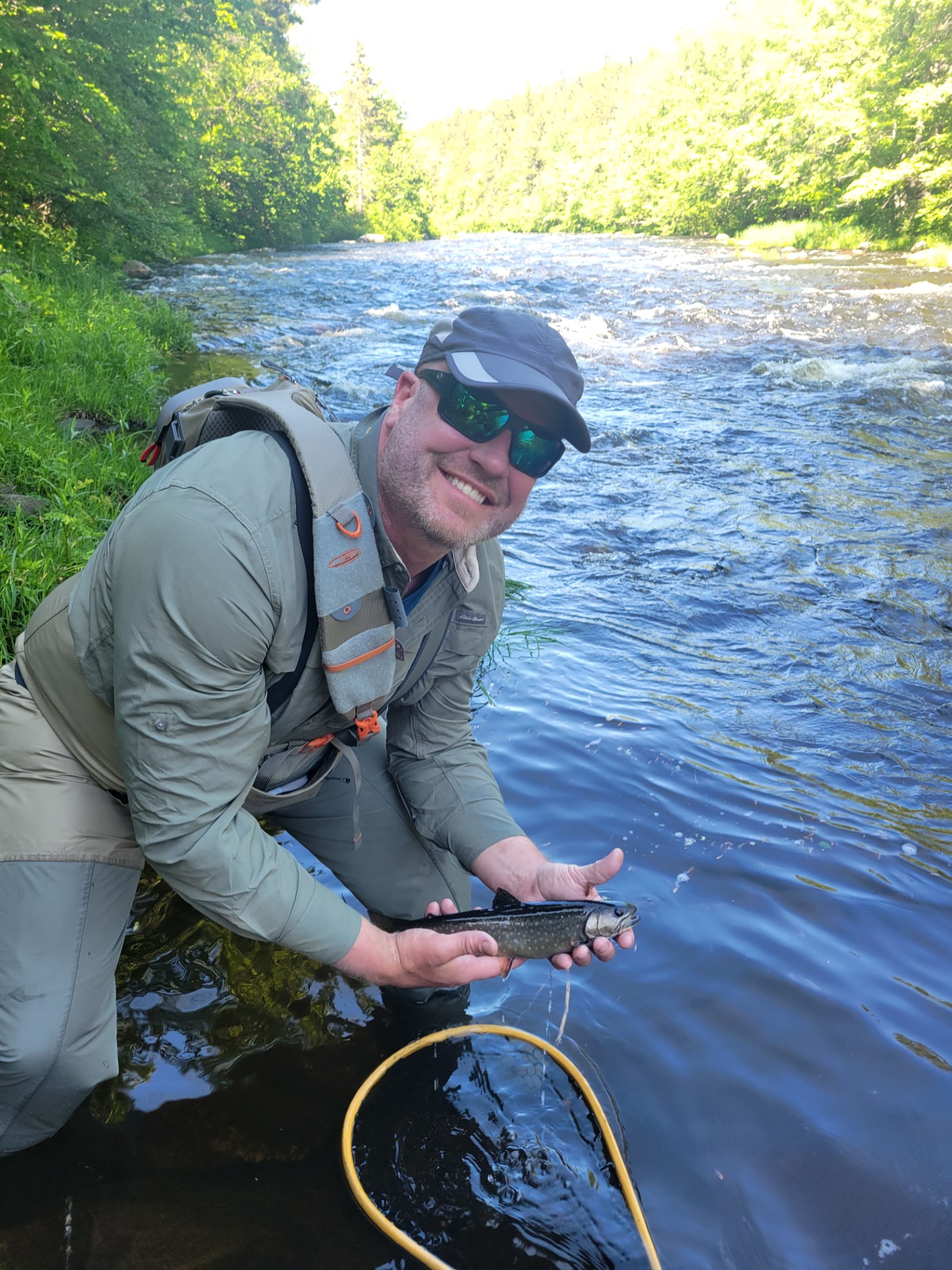 Smiling man by river holding a fish