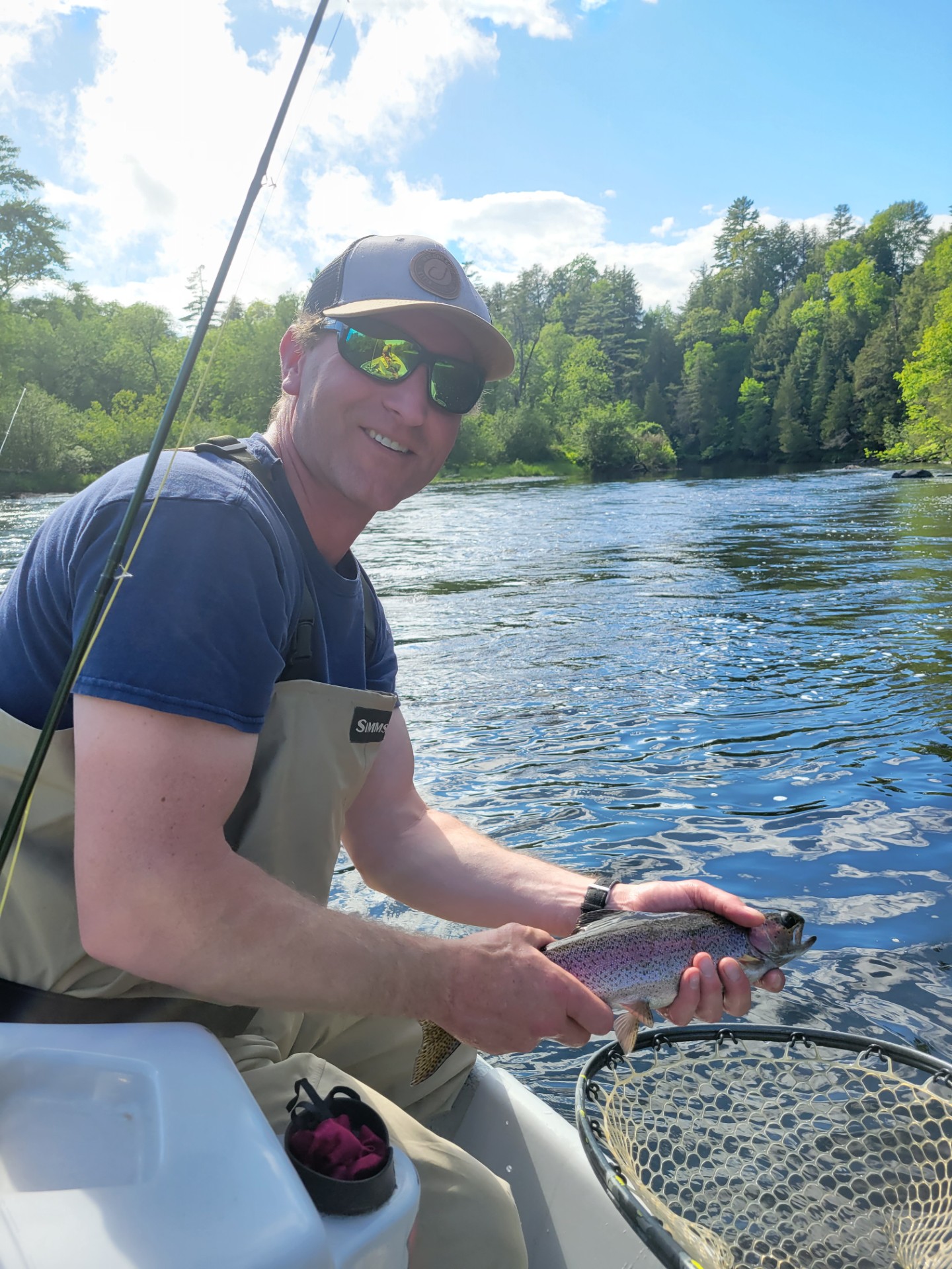 Man smiling holding fish by river