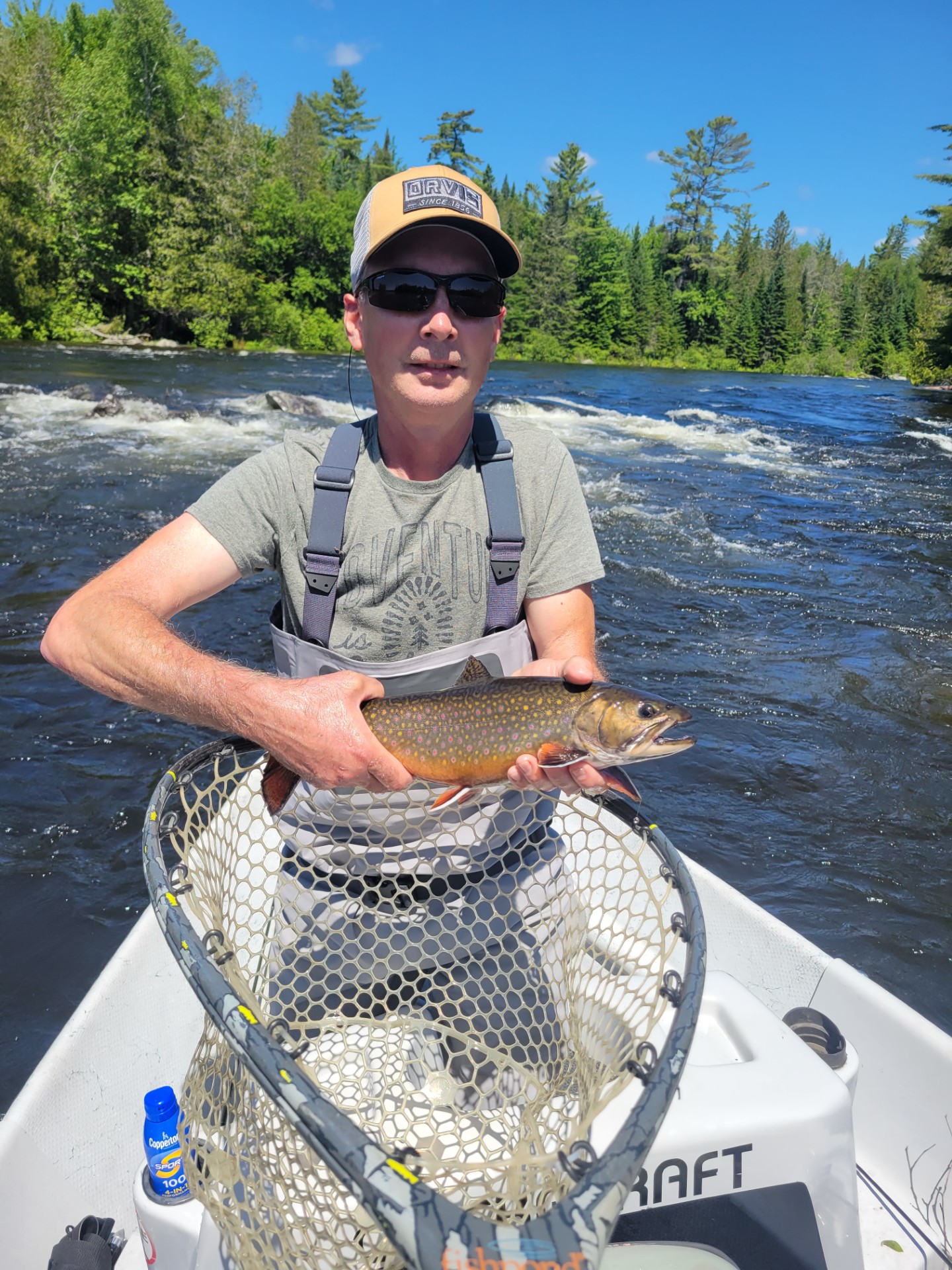 Person standing in boat holding a fish