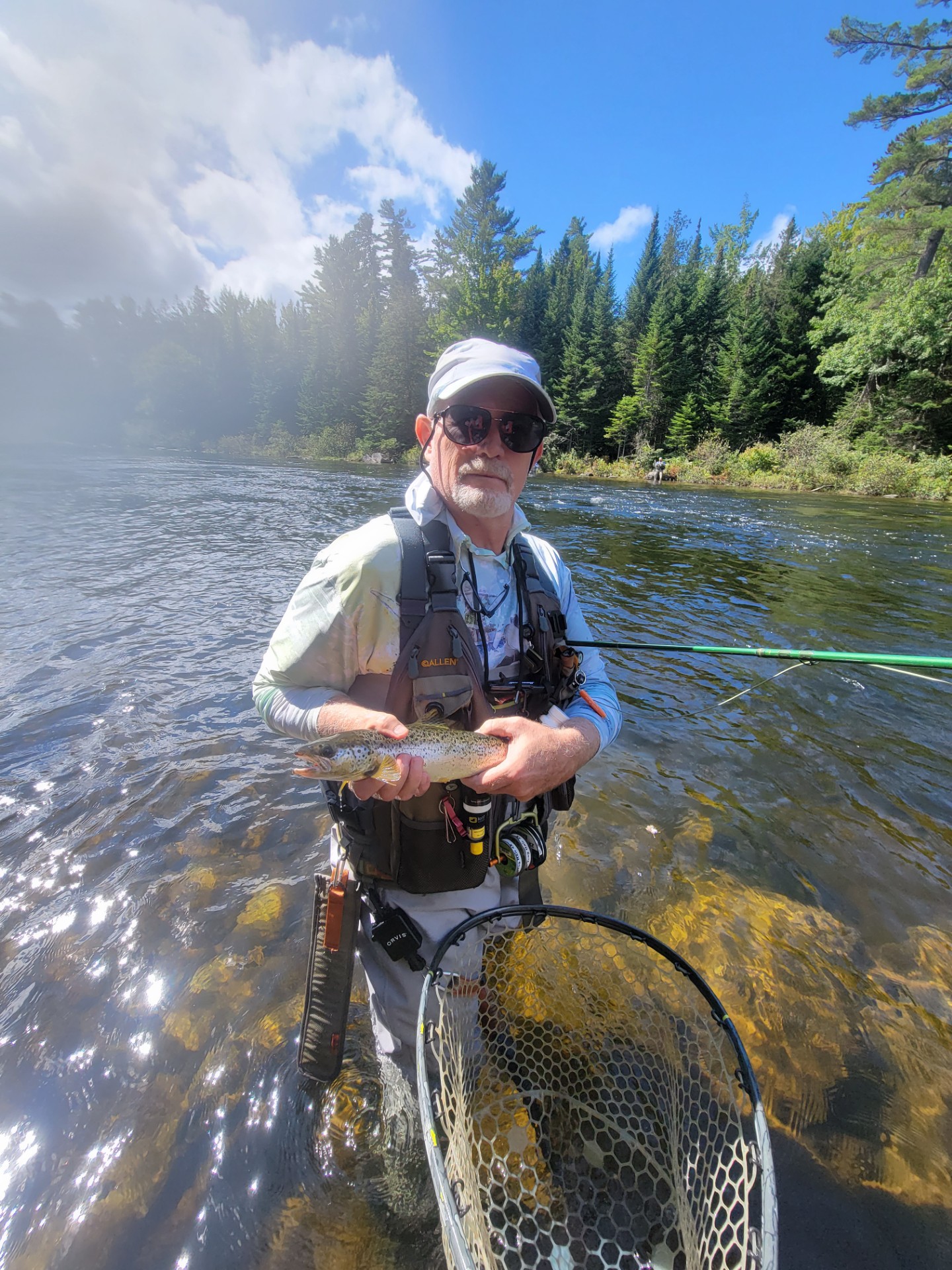 Fisherman standing in a river holding fresh caught fish