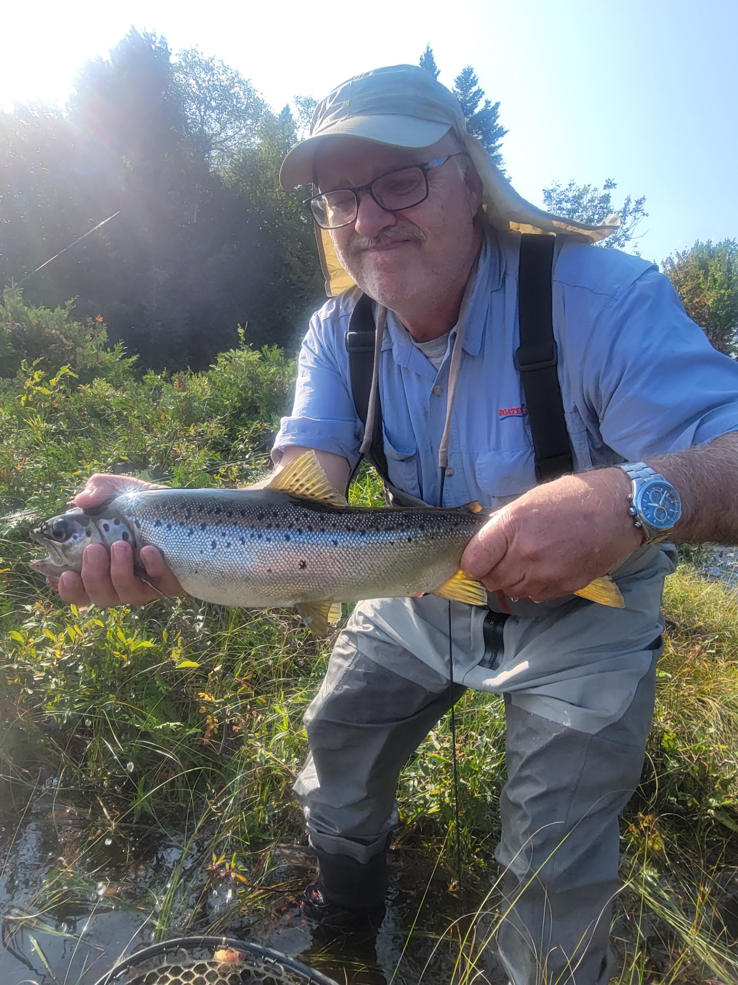 Fisherman standing in a river holding fresh caught fish