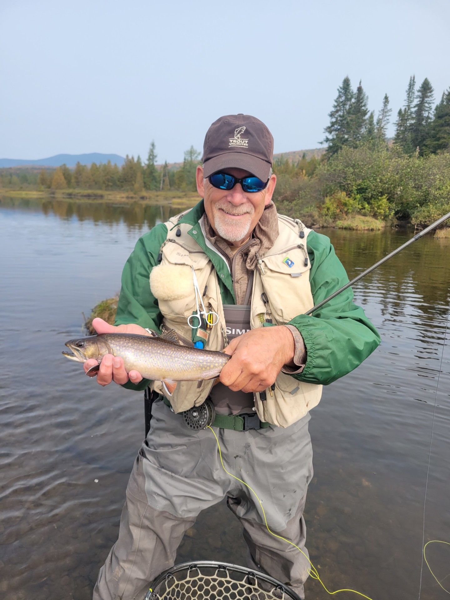 Fisherman standing in a river holding fresh caught fish