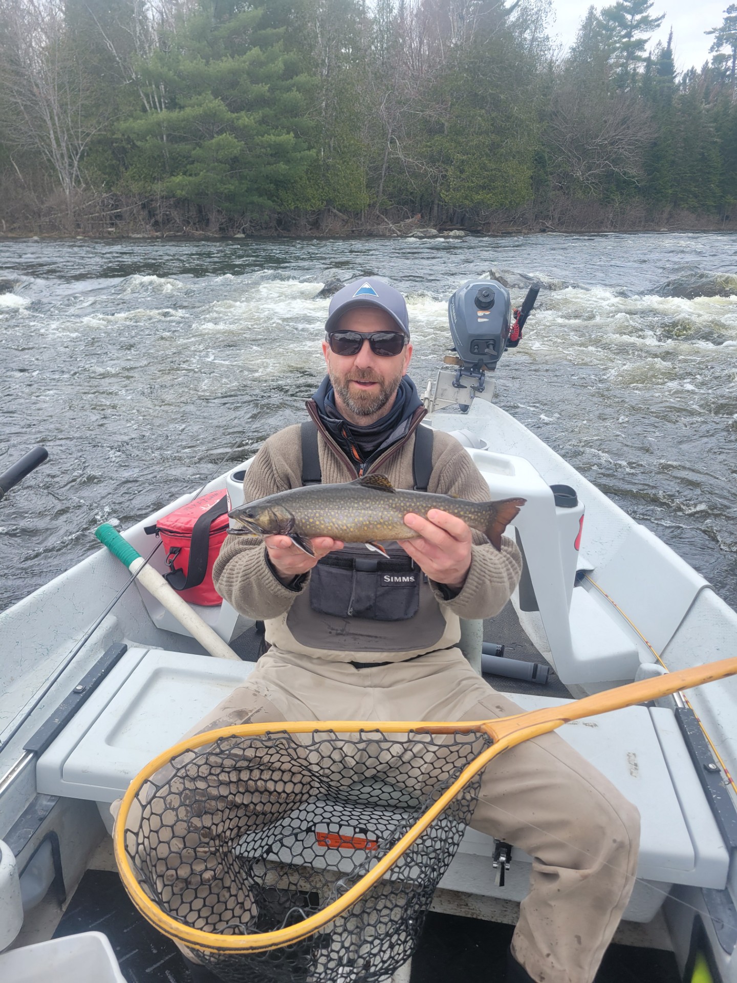Fisherman sitting in a boat holding a fresh caught fish