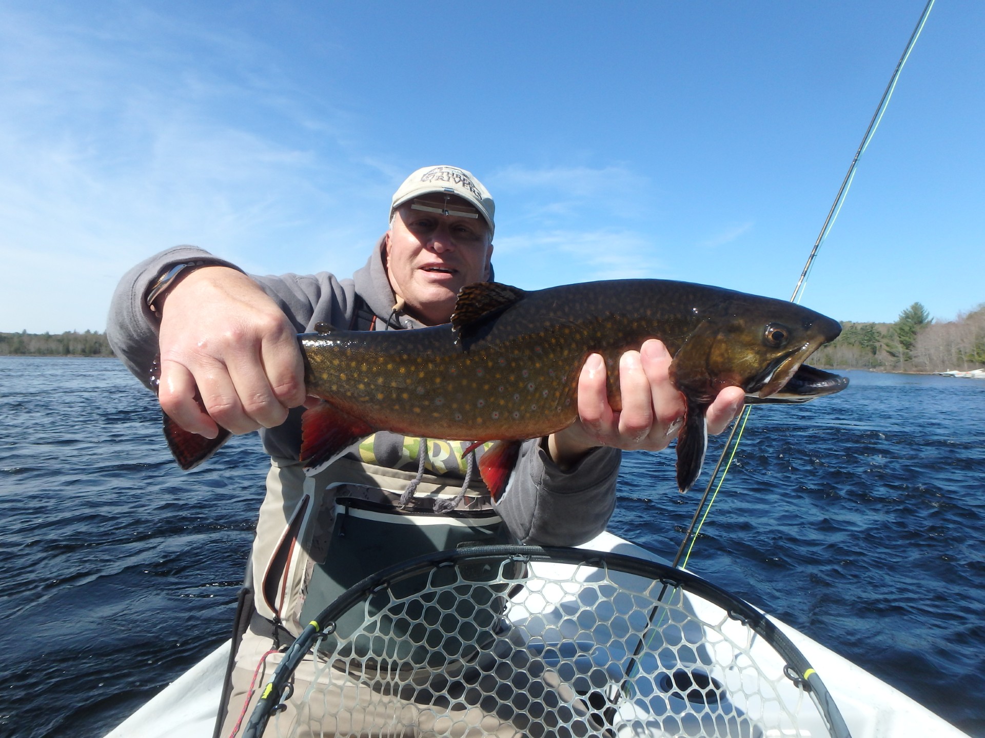 Fisherman sitting in a boat holding a fresh caught fish