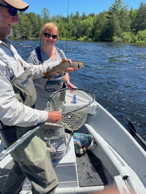 Woman and man on a boat, man holding a fresh caught fish
