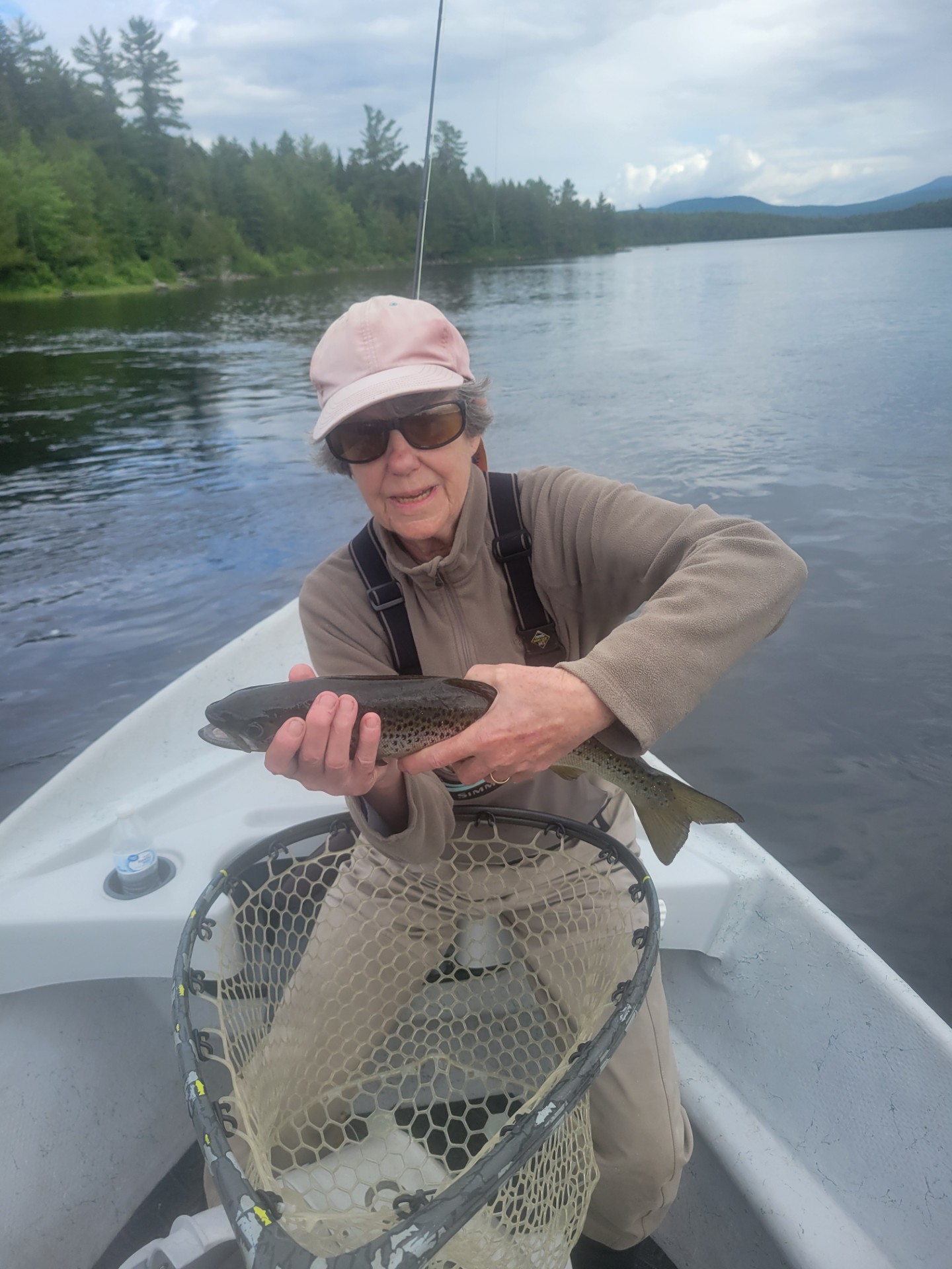 Fisherwoman sitting in a boat holding a fresh caught fish
